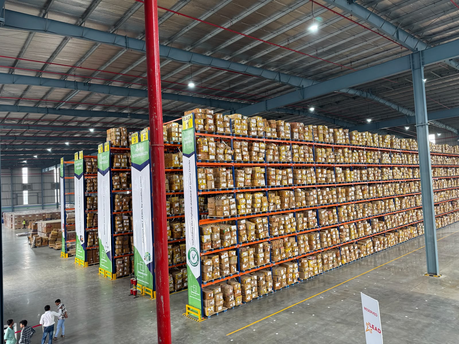 Tall high-bay pallet racking fully stocked in a large distribution warehouse.