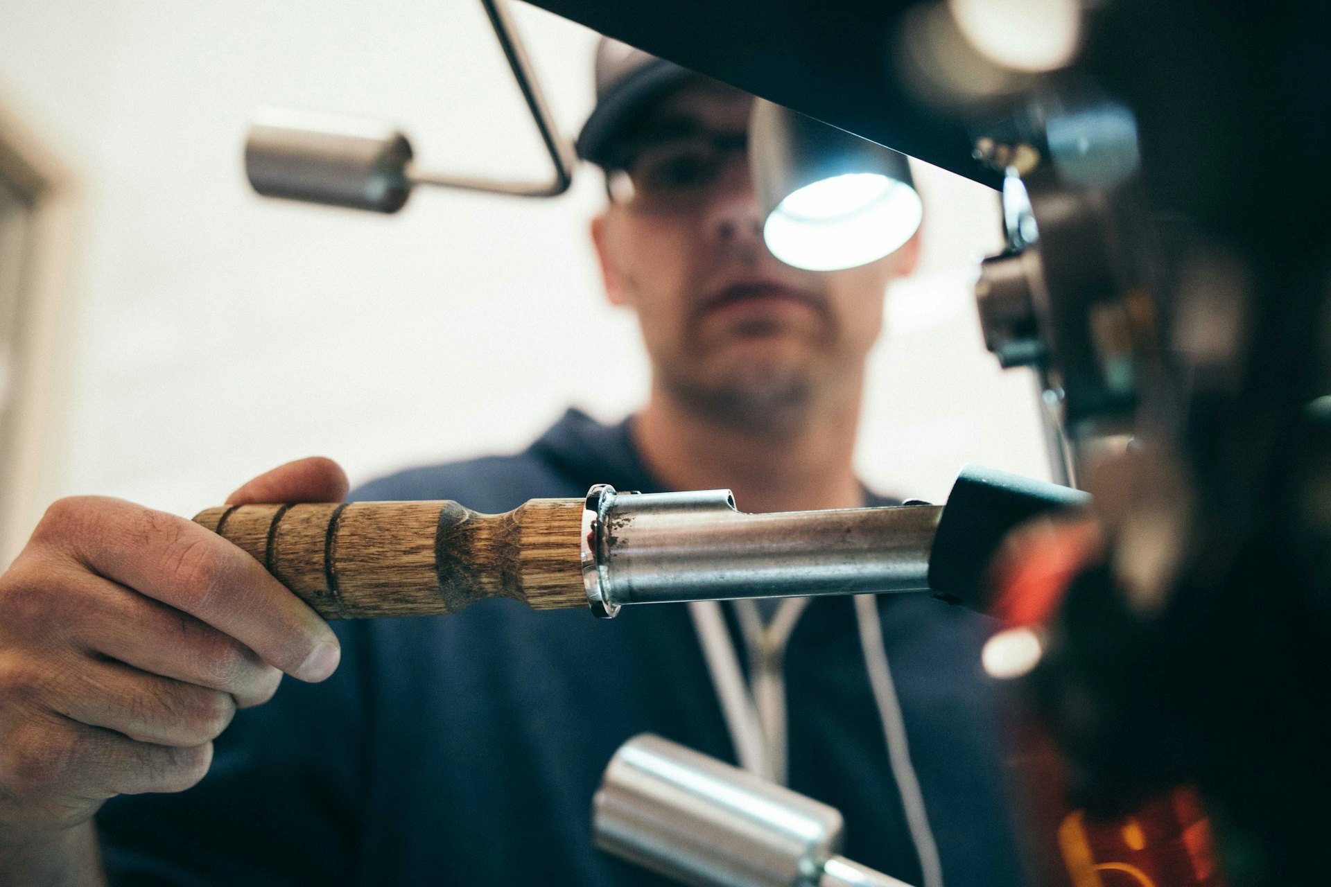 A worker measuring a machined part with a precision caliper on a factory floor.