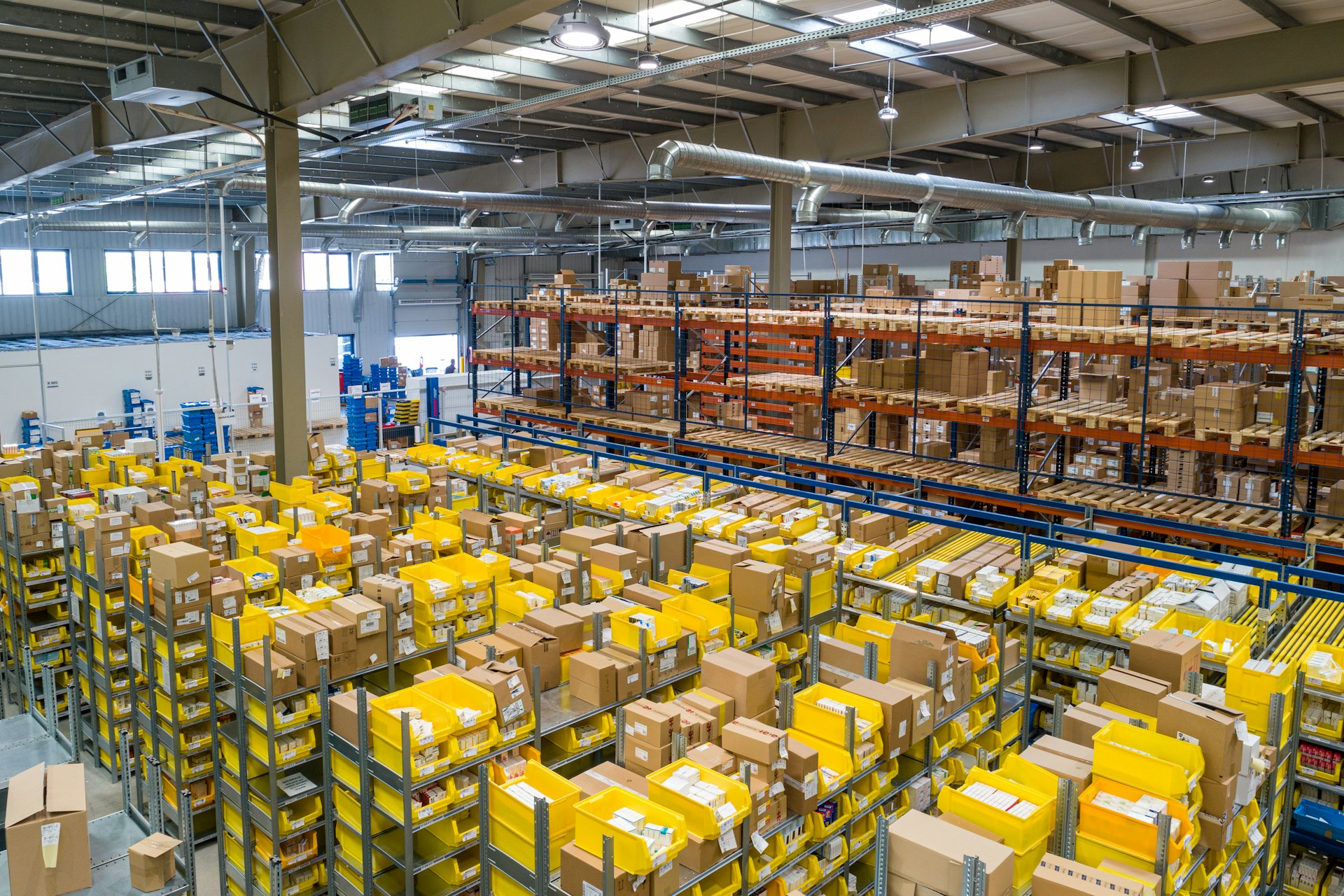 The wide interior of a modern distribution warehouse with rows of storage and a clear-span roof.